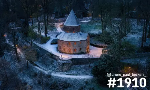 Luchtfoto van de Sint-Nicolaaskapel op het Valkhof in Nijmegen in de winterschemering, met sneeuw en verlichte ramen