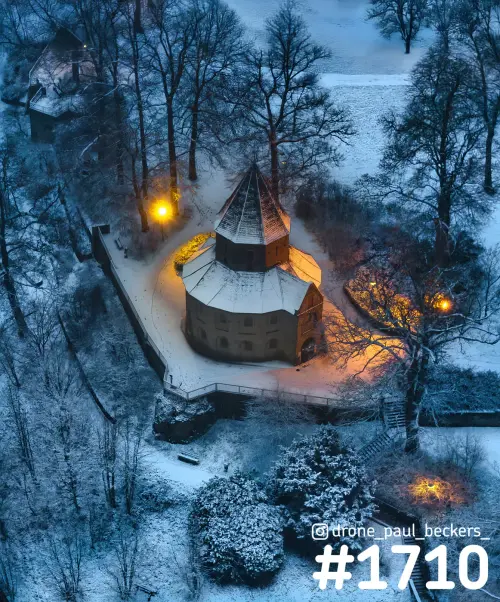 Luchtfoto van een kapel in het Valkhofgebied in Nijmegen, met sneeuw op de daken en warm lantaarnlicht in de avond