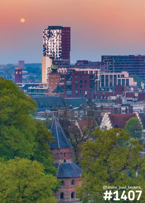 Luchtfoto van het Valkhof gebied in Nijmegen met toren Nimbus, een kapel met leien dak en de maan in roze schemerlicht