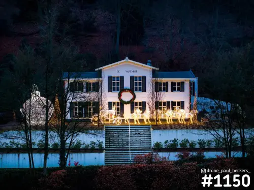 Villa De Varenhof in Beek-Ubbergen in de schemering, met verlichte kerstkoets, lichtgevende paarden en een grote kerstbal