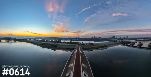 Panorama van de Waal bij Nijmegen-Lent in de schemering, met oranje gloed aan de horizon en een brug op de voorgrond