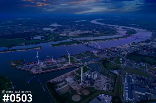 Luchtfoto van de Waal in Nijmegen in de schemering, met De Oversteek, havenkade met containers en windturbines