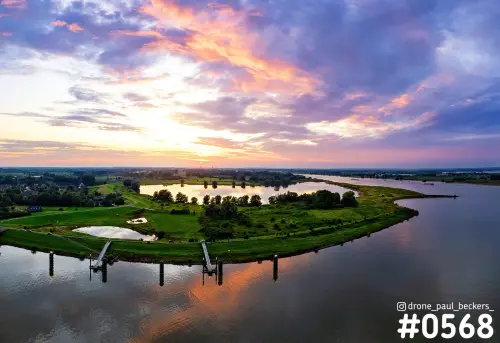 Luchtfoto van de Waal bij Weurt met een kleurrijke zonsondergang, een groene uiterwaard met plas en twee aanlegsteigers in het water