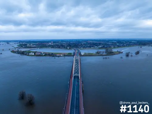 Luchtfoto van de Waalbrug in Nijmegen bij hoogwater, met overstroomde uiterwaarden en Lent aan de overkant van de Waal