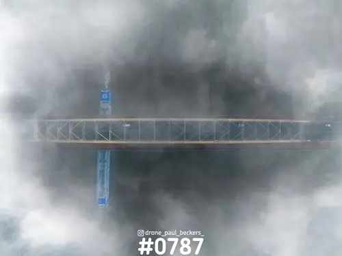 Luchtfoto recht van boven van de Waalbrug in Nijmegen in dikke mist, met een blauw binnenvaartschip op de Waal