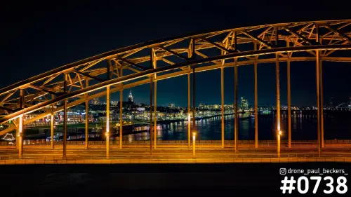 Waalbrug in Nijmegen bij nacht: oranje verlichte stalen boog met zicht op de Waalkade en de weerspiegeling in de Waal