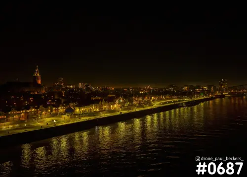 Luchtfoto van de Waalkade en de Stevenskerk in Nijmegen bij nacht, met lichtreflecties op de rivier de Waal
