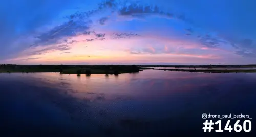 Panoramische luchtfoto van de Waal bij Weurt na zonsondergang, met roze en blauwe wolkenlucht die weerspiegelt in het water