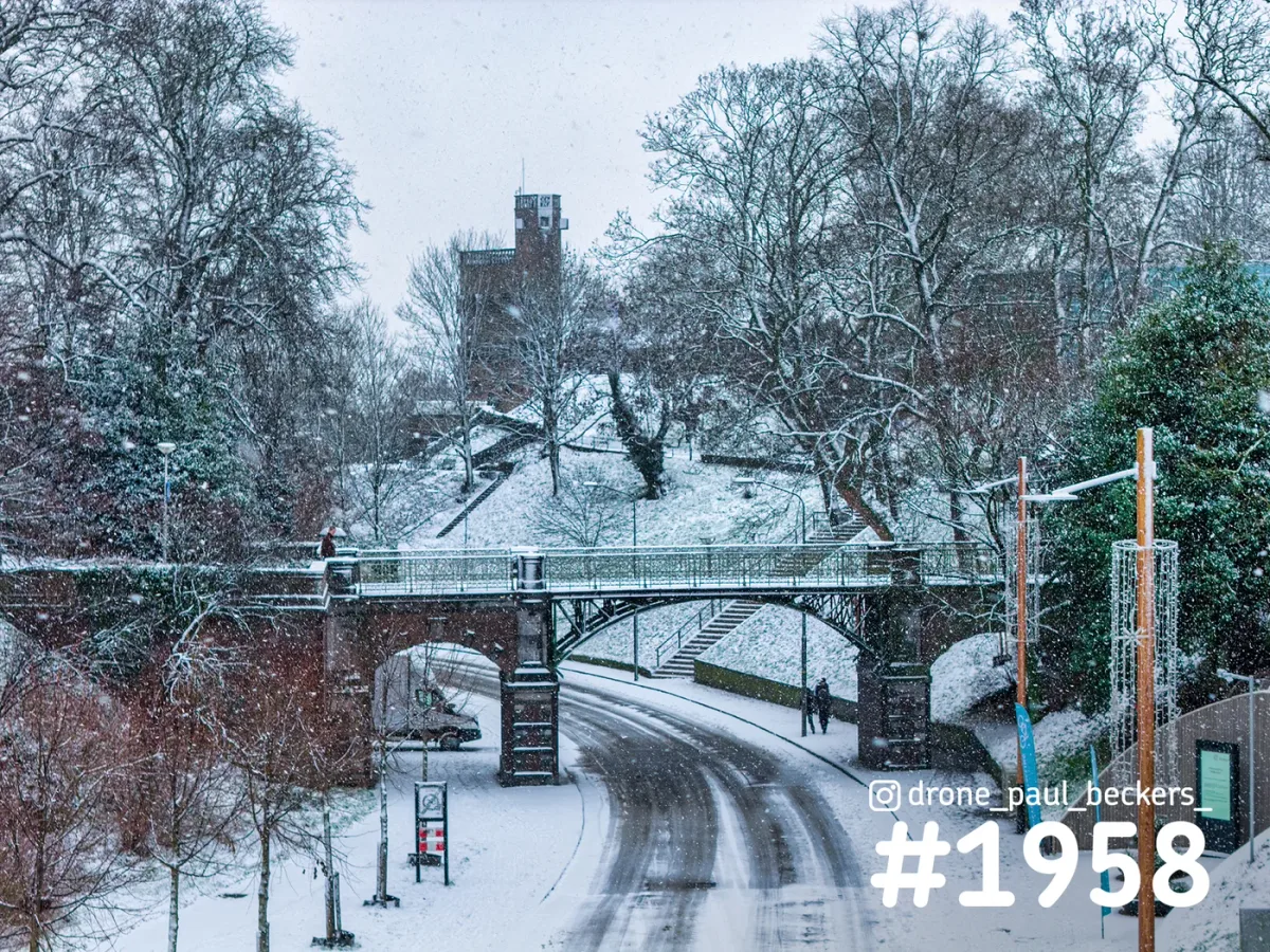 Stenen boogbrug over een besneeuwde weg in het Valkhof gebied in Nijmegen, met sneeuwval en kale bomen