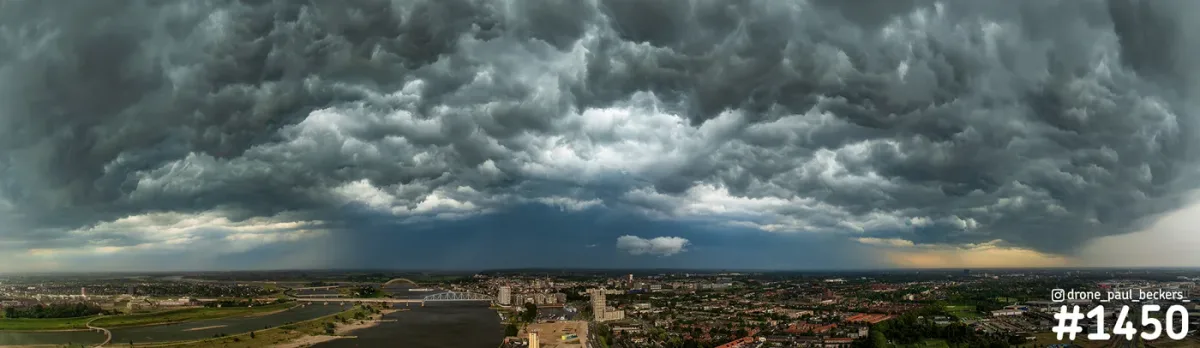 Luchtfoto panorama van een donkere onweerslucht boven de Waal en Nijmegen-Lent, met een regenbui aan de horizon