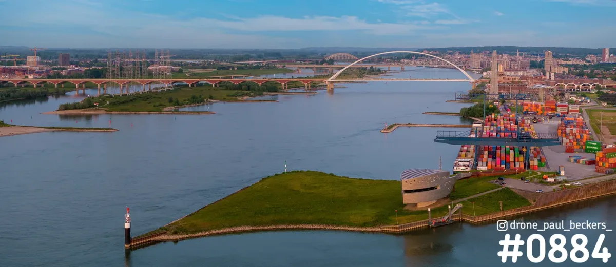 Luchtfoto van De Oversteek over de Waal in Nijmegen, met gekleurde containers in de haven in warm zonlicht
