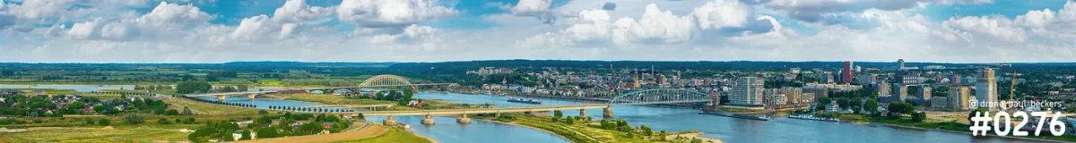 Panoramische luchtfoto van de Waal bij Nijmegen met Waalbrug en Handelskade onder een blauwe lucht met wolken